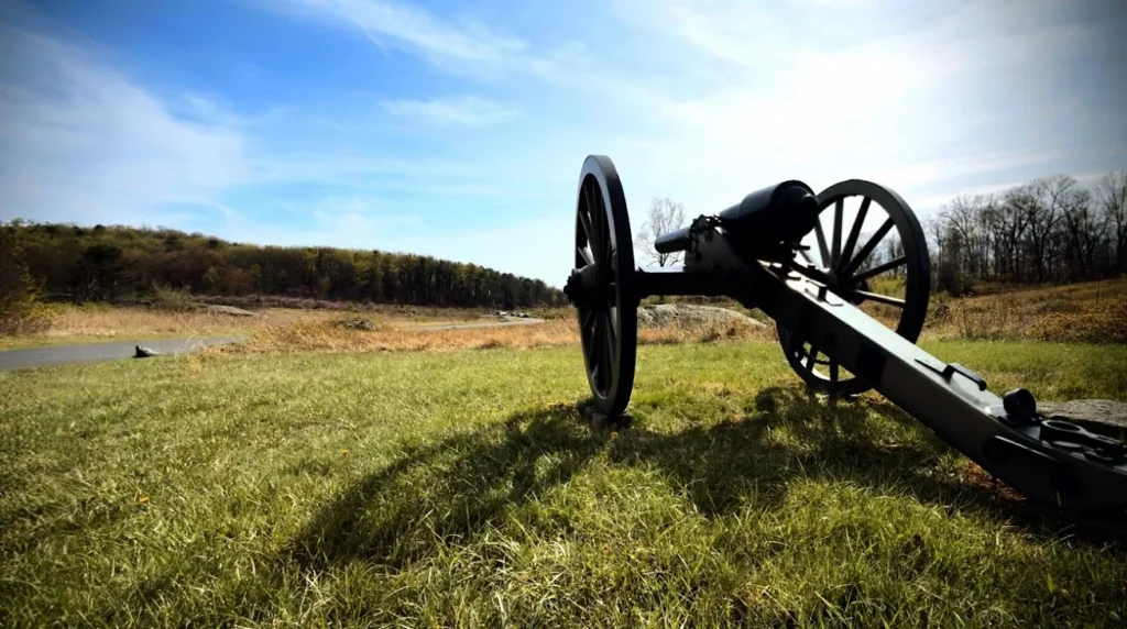 Low-angle photo of a Civil War cannon on the Gettysburg battlefield under a blue sky
